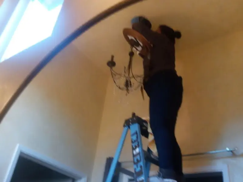 Electrician installing a chandelier in a Mansfield residence